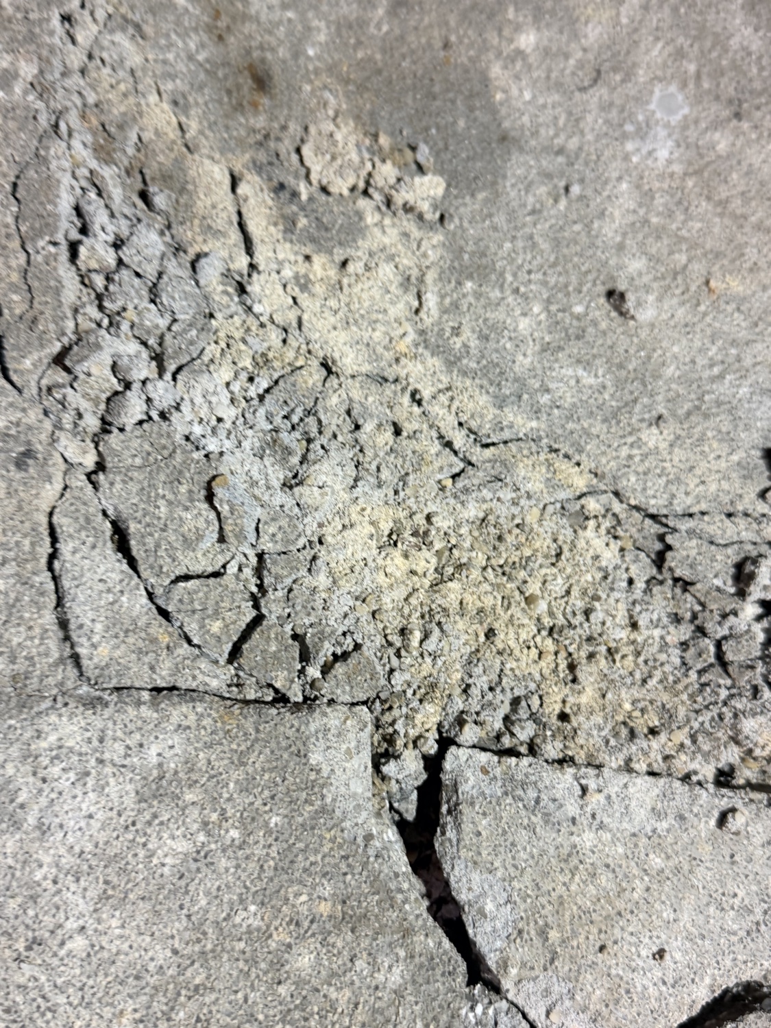 Close-up of a cracked, crumbling concrete floor surface