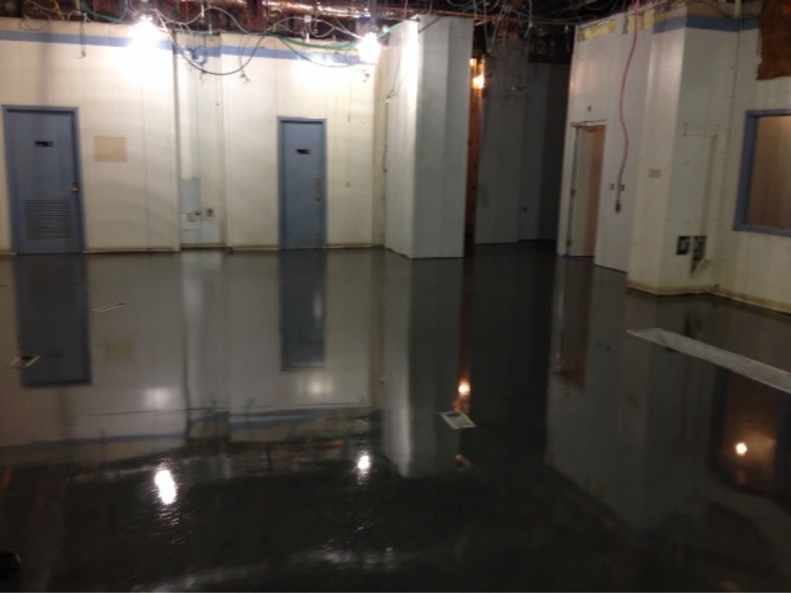Dark high-gloss epoxy floor reflecting the walls and doors of an industrial backroom