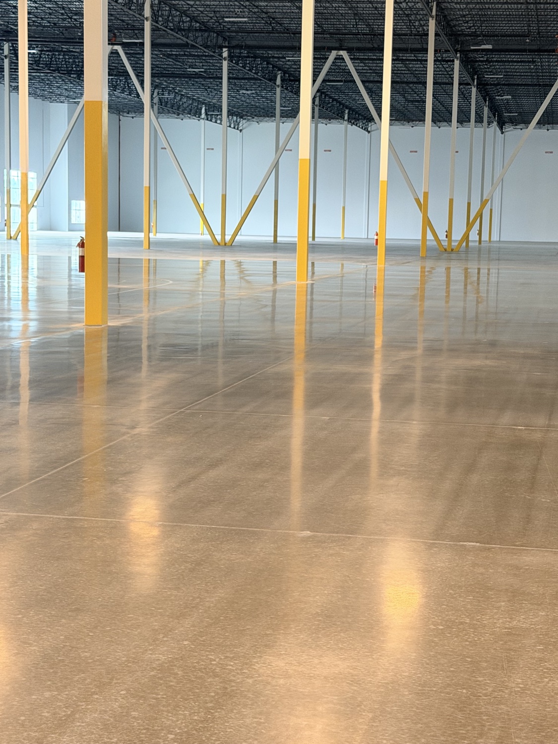 Portrait view down a mirror-polished warehouse floor between columns