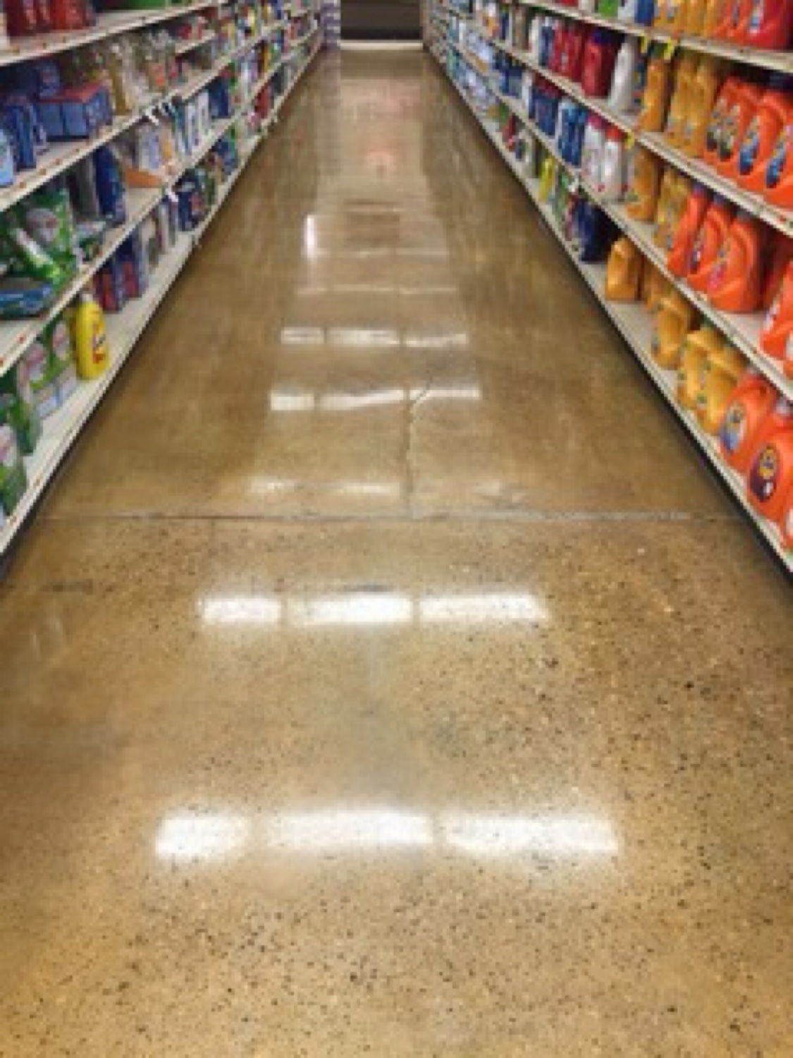 Tan polished concrete floor running down a stocked grocery aisle
