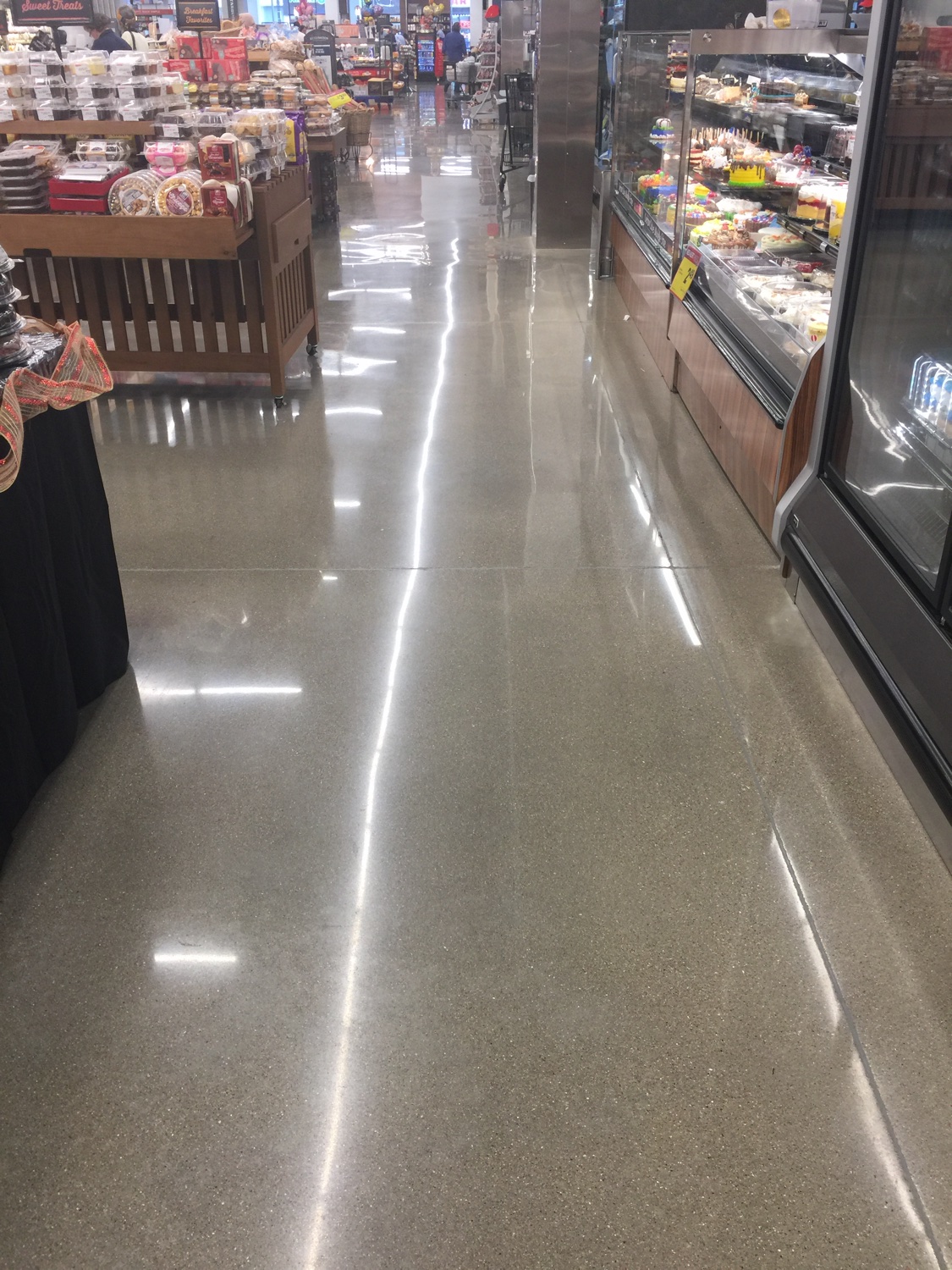 Mirror-polished concrete floor running alongside a grocery bakery case