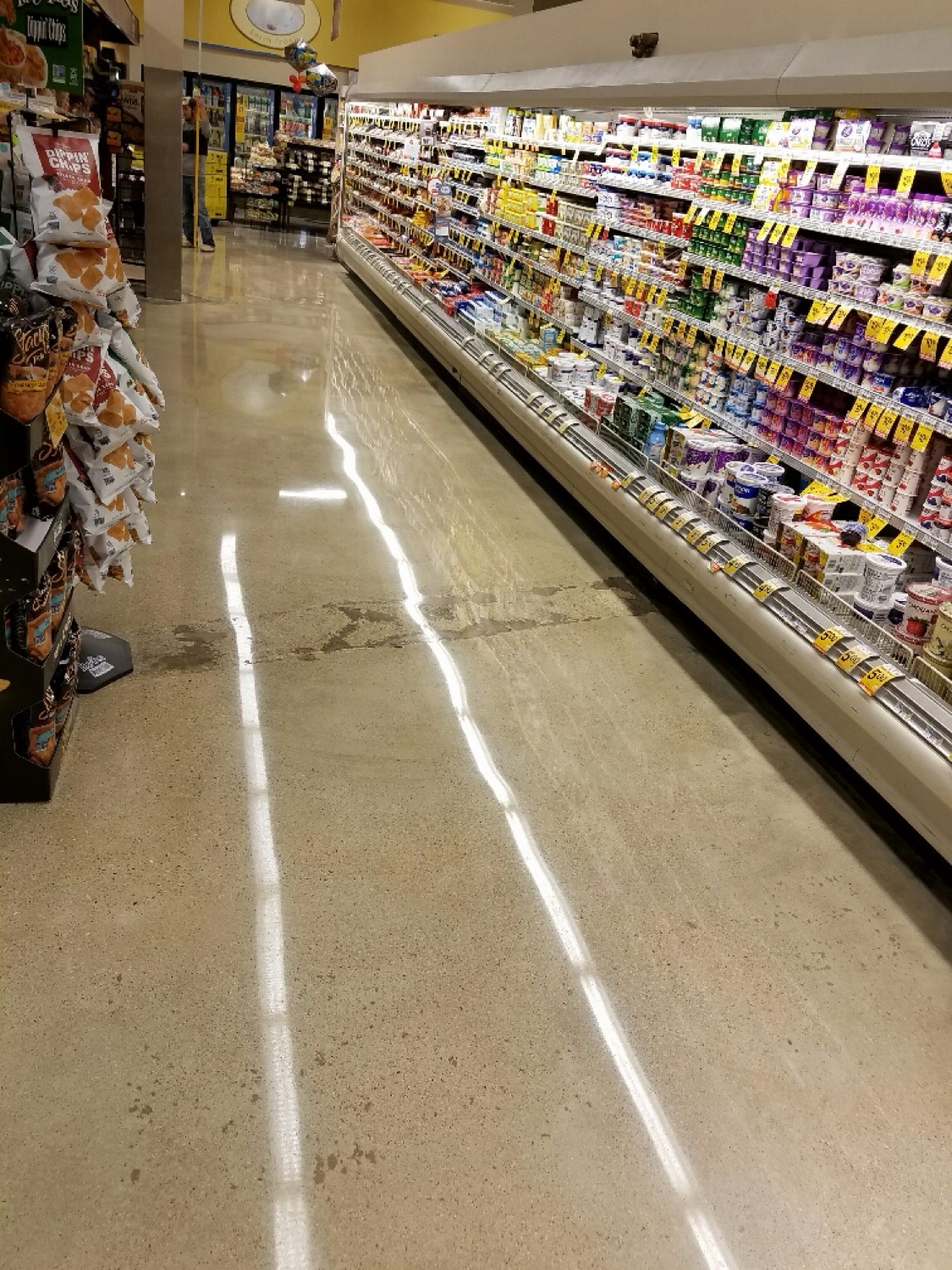 Polished concrete floor reflecting the case lights along a grocery dairy aisle
