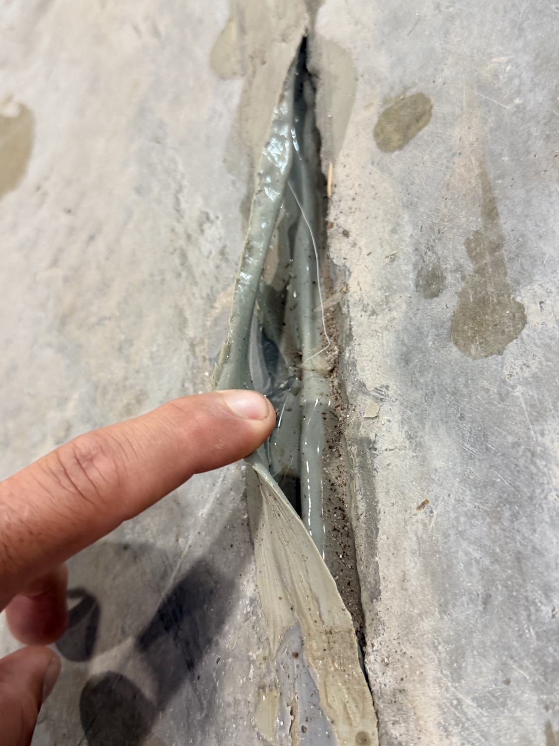 A strip of failed joint filler being pulled out of the joint by hand