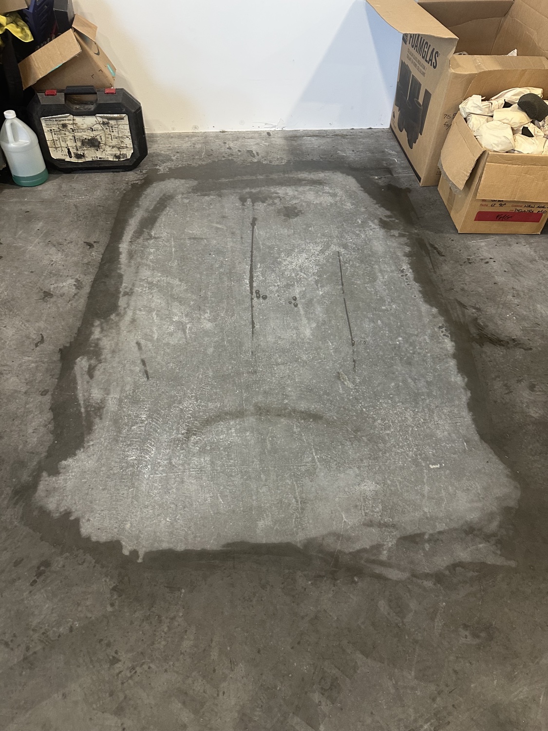 Moisture-stained patch darkening the slab in a small finished room