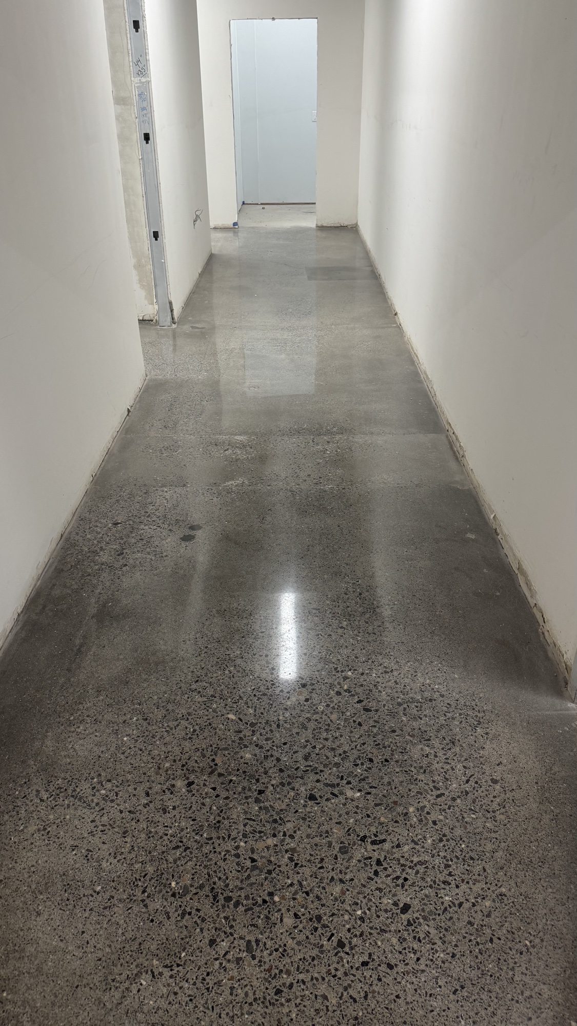 Polished concrete hallway with heavy exposed aggregate running to a doorway