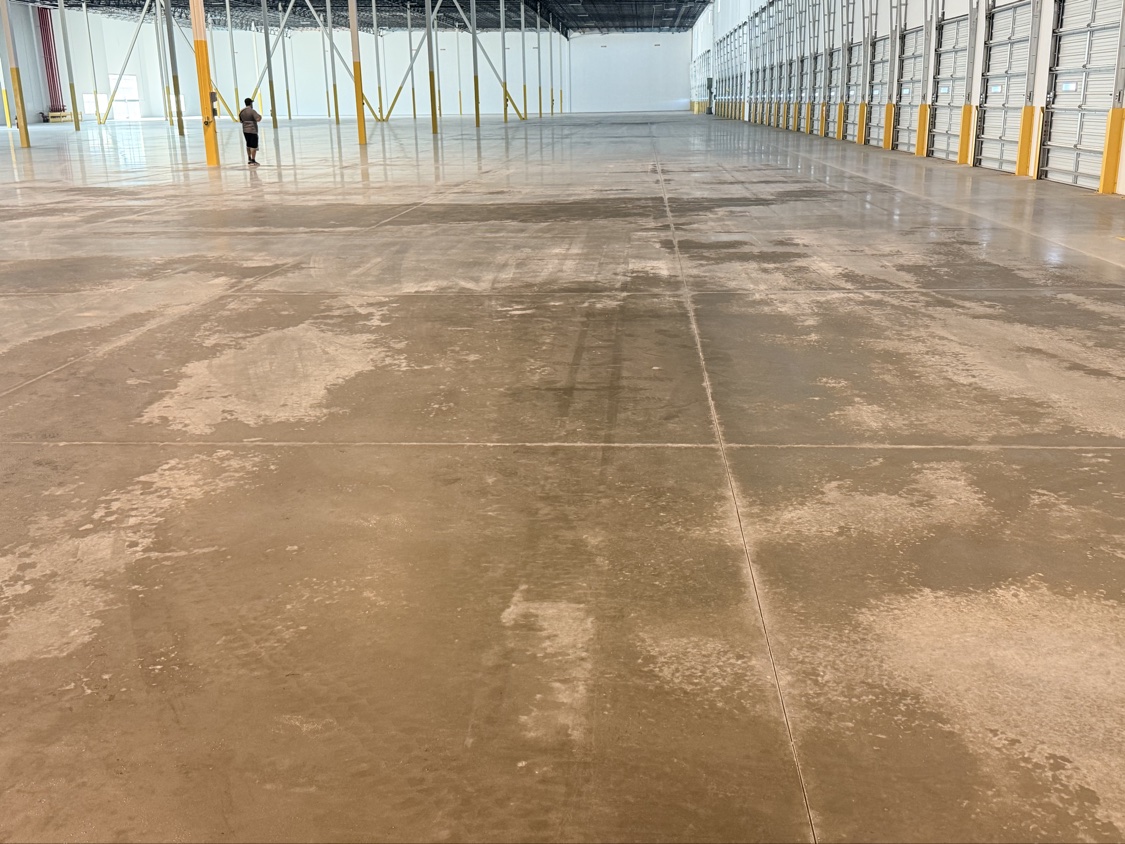 Moisture-marked warehouse floor stretching across a full aisle