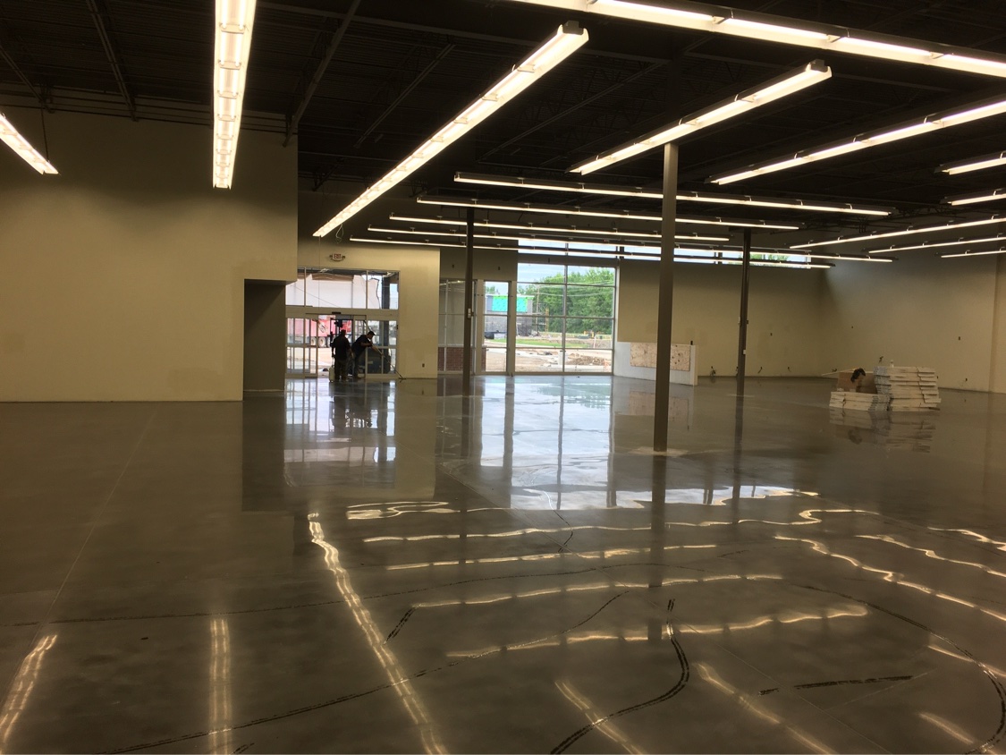 Stained polished concrete floor reflecting the storefront glass in an empty retail shell