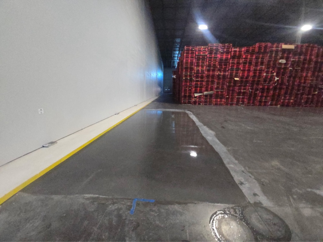 Freshly treated strip of warehouse floor with a wet-look gloss beside untreated concrete